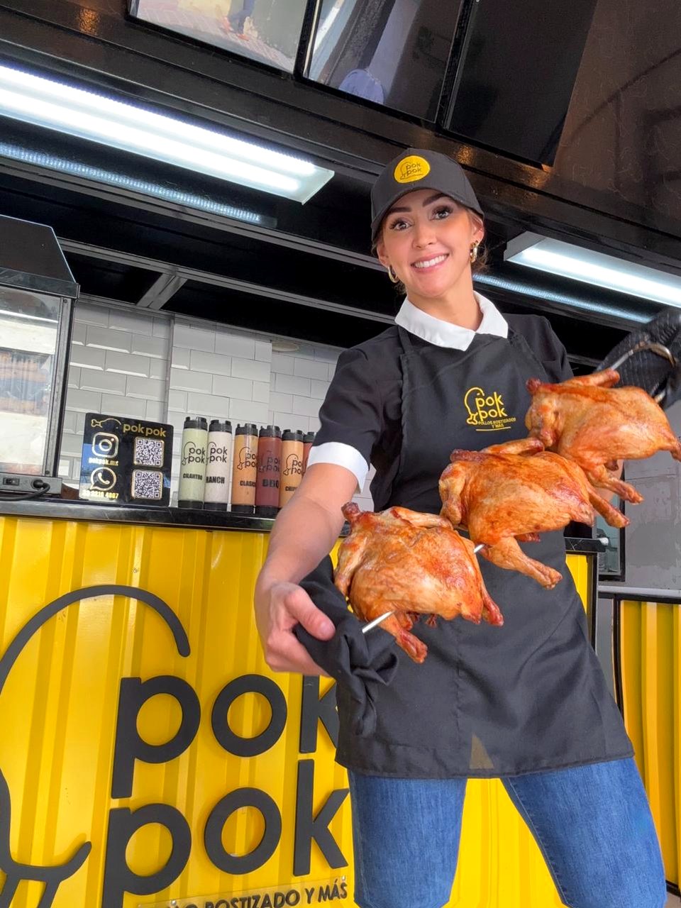 Equipo Pok Pok mostrando pollo rostizado frente a la cocina